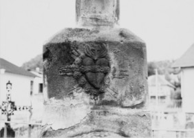 Un cœur enflammé est représenté dans une nuée rayonnante, à la base de la croix, ainsi que sur le socle (photographie du service régional de l'inventaire de Lorraine).