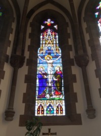 Le vitrail central du chœur de l'église de Haspelschiedt représente le groupe du Calvaire.