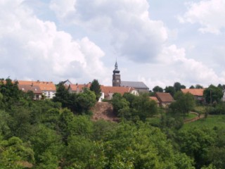 Le village de Liederschiedt, posé sur le rebord du plateau, surplombe la vallée du Grunnelsbach. La silhouette de l'église Saint-Wendelin domine la masse des maisons avec son toit coiffé d'ardoise.