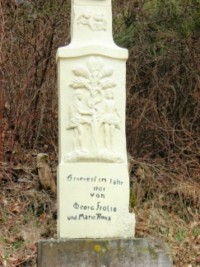 Le fût-stèle représente Adam et Eve en Paradis, une scène fort peu fréquente sur les croix de chemin de la région.