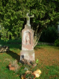 Une croix de chemin, creusée d'une niche abitant une sculpture en bas-relief de Notre-Dame de Lourdes, est érigée en bordure de la rue principale du village de Reyersviller.