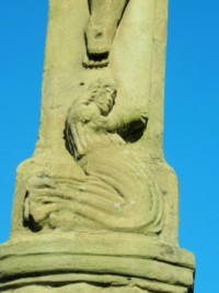 La partie inférieure du croisillon de la croix située désormais près du presbytère.