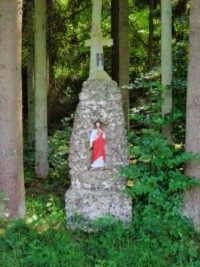 En bordure de la rue de la fontaine, une croix est élevée et abrite une statuette du Sacré-Cœur dans une niche.