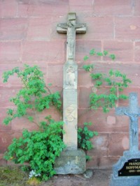 La croix, adossée au chevet de l'église dans le cimetière, est érigée en 1707.