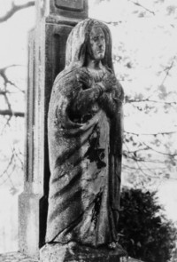 La Vierge du Calvaire est sculptée en ronde-bosse au pied du fût, reposant sur le socle (photographie du service régional de l'inventaire de Lorraine).