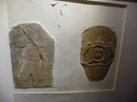 Un demi-relief en grès rose est encastré dans le mur Nord de la tour-clocher de l'église paroissiale de Sturzelbronn. Représentant un moîne, il semble dater du XVIe siècle. Dans un état moyen de conservation, il présente les angles inférieurs de la pierre cassés, de même que la volute et l'extrémité de la crosse, ainsi qu'un gros éclat sur la partie droite de la tête du religieux. Un bas-relief, dans le même mur, figure des armoiries : un écu couronné chargé de trois cœurs retournés, accosré de deux chiens. D'après Boulangé, qui aurait vu le relief dans le cimetière, l'inscription présente sous le clocher figurait au revers des armoiries.