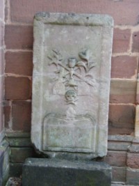 Une pierre tombale est adossée à la tour-clocher. Elle présente des attributs sacerdotaux tels que l'étole et le calice, ainsi que le symbole macabre de la tête de mort.