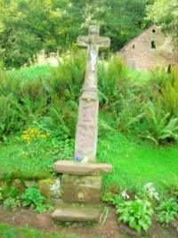 Une croix de chemin, portant l'inscription peut-être surajoutée de 1827, est érigée à proximité de la chapelle Sainte-Vérène. Elle représente les effigies de saints protecteurs ruraux : sainte Vérène en habits de paysanne du XIXe siècle, saint Marc avec le lion et la palme du martyre et saint Wendelin avec le chien et la houlette de berger.