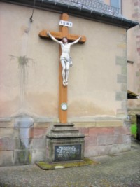Une croix de mission est adossée au mur arrière de la sacristie.