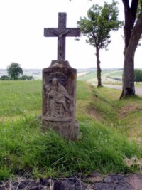 Une croix de chemin se dresse dans la rue des chevaliers,  la sortie du village de Kalhausen. Le ft-stle reprsente une Piet, tandis que le croisillon original a t remplac par un nouveau croisillon en bton.