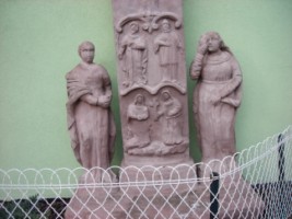 Les statues en ronde bosse de la Très Sainte Vierge et de saint Jean entourent le fût de la croix.