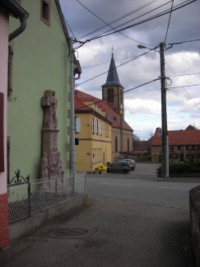 La croix est adossée à la façade latérale de la maison 16, rue d'Alsace.