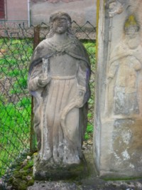 Une statue en ronde bosse de saint Jean encadre le fût de la croix, à gauche.