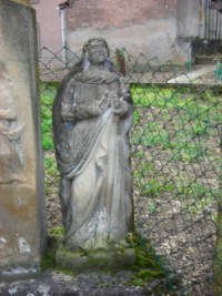 Une statue en ronde bosse de la Sainte Vierge encadre le fût de la croix, à droite.