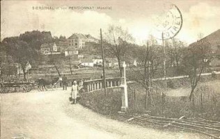 Le carrefour central du village : la route nationale arrive de Rohrbach-lès-Bitche et la Frohmühl depuis la droite et continue à gauche vers Reyersviller et Bitche. Le village de Siersthal se situe en retrait de la route, en face sur la photographie. On distingue le pensionnat des religieuses de Saint-Jean-de-Bassel surplombant la localité : détruit durant la dernière guerre, il est aujourd'hui transformé en maison de retraite.