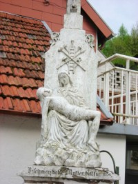 Une croix du village de Siersthal nous présente Notre-Dame de Pitié à la descente de la Sainte-Croix, portant le corps de Son Fils, ainsi que les instruments de la Passion.