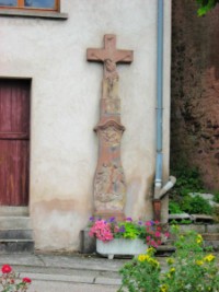 Une croix de chemin adossée à une maison, au début de la rue de la fontaine.
