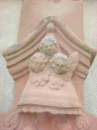 Trois têtes d'angelots ailées sont représentées sur le fût.