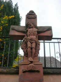 La Très Sainte-Trinité est représentée sur le croisillon de nombreuses croix monumentales, comme ici dans le hameau de Holbach à Siersthal.