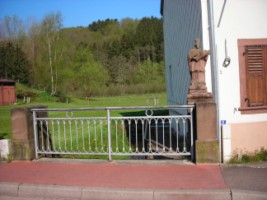 Le statue se situe en bordure du petit pont qui enjambe le ruisseau du Kleinbächel, un affluent de la Schwalb.