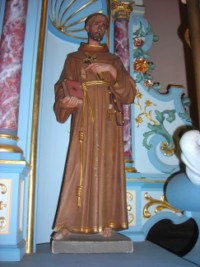Une statue en bois sculpté de saint François d'Assise est située sur l'entablement de l'autel.