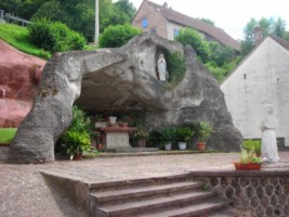 À droite de l'église, une imposante grotte dédiée à Notre-Dame de Lourdes est édifiée, à proximité d'une croix monumentale.
