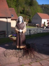 Aux pieds de la grotte, sainte Bernadette lève les yeux vers Notre-Dame.