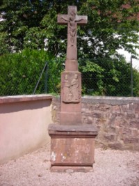 Une croix se dresse dans un angle du cimetire de Bousseviller, entourant encore la petite chapelle Sainte-Odile. En grs rose, elle reprsente deux saints personnages sur le registre suprieur du ft.