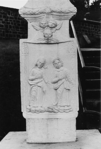 Le fût représente la Très Sainte Vierge et saint Jean encadrés par deux grands cierges, tandis que trois têtes d'angelots ailées les surplombent (photographie du service régional de l'inventaire de Lorraine).