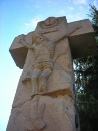Le crosillon représente le Seigneur Jésus en Croix, surmonté d'une tête d'angelot ailée.