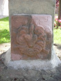 Un cœur enflammé, entouré de roses, est représenté au pied du fût-stèle.