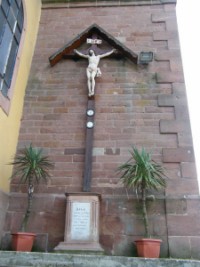 Une croix de mission est adossée à la tour-clocher de l'église Saint-Hubert de Breidenbach.