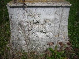 Sur le socle figure la Sainte-Croix, sur laquelle se dresse l'Agneau vainqueur porte-étendard.