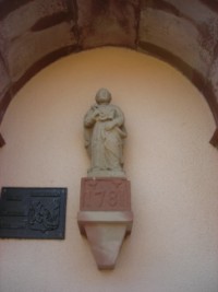 Une belle statue en pierre de saint Pierre trône contre la façade latérale de l'église, abritée par un auvent.