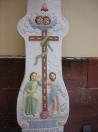 le fût représente les personnages bibliques d'Adam et Ève, situés de part et d'autre d'une croix fleurdelisée, autour de laquelle est enroulé un serpent.