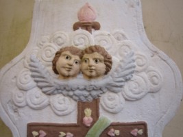Deux têtes d'angelots ailées sont situées au sommet du fût.