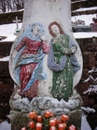 La Très Sainte Vierge et saint Jean, habillés à la façon du XVIIIe siècle, occupent le registre inférieur du fût-stèle.