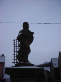 Tenant en main le grill de son martyre, saint Laurent domine la fontaine de grès rose.