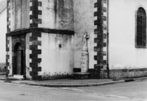 La croix est adossée à la façade occidentale de l'église Saint-Wendelin, à droite de la porte (photographie du service régional de l'inventaire).