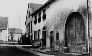 La rue de Bitche au début du XXe siècle, en contrebas de l'église : la maison d'œuvres à gauche et la maison d'Antoine Meyer à droite.