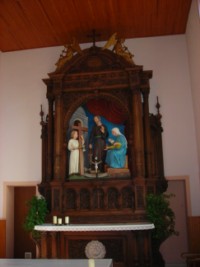 Le maître-autel de la chapelle est surmonté d'un très beau retable en bois, représentant la Sainte Famille : la Sainte Vierge file, tandis que saint Joseph enseigne à l'Enfant-Jésus le travail du bois, Celui-ci réalisant déjà Sa Croix.