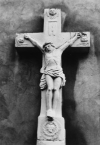 Trois têtes d'angelots ailées encadrent le Christ en Croix du croisillon.