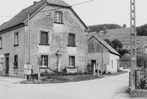 La croix est adossée à la maison faisant l'angle entre les rues des prés et du stade.